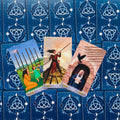 Tarot kortos trijų kortų išklotinė su mėlynais galais, centre trys figūrinės kortos atverstos skirtingais kampais