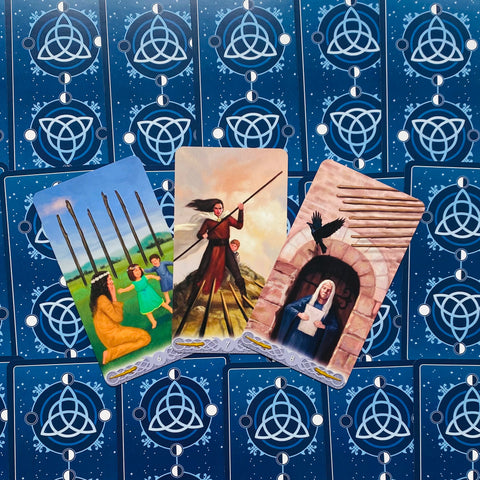 Tarot kortos trijų kortų išklotinė su mėlynais galais, centre trys figūrinės kortos atverstos skirtingais kampais