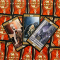 Tarot kortos dragonų tematikos, raudono‑auksinio nugarėlių fono, trigubas artimas planas su iliustracijomis ir riteriais