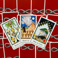 Tarot kortos Rider–Waite stiliaus, trys dubenų kortos (7, 8, 9) ant raudonų gyvatės rašto nugarėlių, persidengiančios kampu