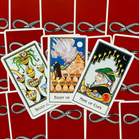 Tarot kortos Rider–Waite stiliaus, trys dubenų kortos (7, 8, 9) ant raudonų gyvatės rašto nugarėlių, persidengiančios kampu