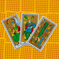tarot kortos Marseille stiliaus rinkinyje, trikampis išdėstymas: karalienė, karalius ir lazda ant geltono raštuoto fono