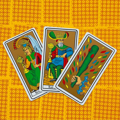 tarot kortos Marseille stiliaus rinkinyje, trikampis išdėstymas: karalienė, karalius ir lazda ant geltono raštuoto fono