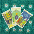 tarot kortos su žaliais ornamentuotais nugarėliais, nuotraukoje trys atviros Pentaklių kortos iš viršaus — variantas su pavyzdine išdėstymo kompozicija
