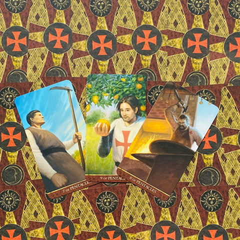 Tarot kortos – trys Pentaklių kortos (7, 9, 8) iš komplekto, kampu išdėstytos ant bordo‑aukso ornamentuotos nugarėlės