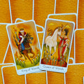 Tarot kortos komplektas su Karaliumi ir Karaliene (Wands), oranžinis fonas, persidengiančios kortos su vienaragiu