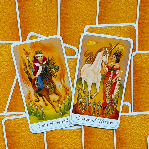 Tarot kortos komplektas su Karaliumi ir Karaliene (Wands), oranžinis fonas, persidengiančios kortos su vienaragiu