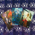 Tarot kortos su violetiniu simboliniu nugarėliu, trys priekinės kortos (Karalius, Karalienė, Riteris Pentaklių) su fentezi iliustracijomis