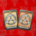 Tarot kortos, dvi kortos The Wanderer (kreminė) ir The Witness (persikinė) su metaliniais žiedais ant raudono simbolinio fono