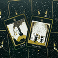 Tarot kortos katėmis, juodos ir auksinės, dvi išverstinės kortos (Three of Cups ir Four of Cups) pateiktos ant žvaigždėto fono