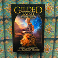 Produkto puslapyje — priekinis Gilded Tarot Royale taro rinkinio viršelis: juoda dėžutė, raudonplaukė moteris ir liūtas