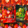 Soul Helper Oracle kortų rinkinys raudonoje dėžutėje, rodoma priekinė pakuotė su viena ištraukta žalia korta, pabrėžianti iliustracijų kontrastą