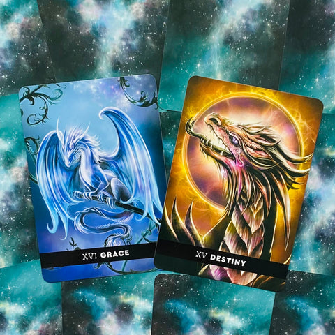tarot kortos su drakonų iliustracijomis: mėlyna XVI Grace ir auksinė XV Destiny ant žvaigždėto fono, žiūrima iš viršaus