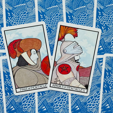Tarot kortos – dvi atviros Pentaklių kortos (Page ir Knight), rodomos įstrižai, priekiniai piešiniai ir mėlynas nugarėlių raštas matomi