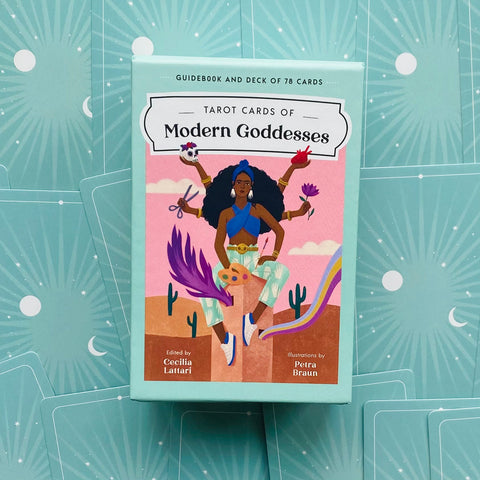Tarot kortos Modern Goddesses žalsvai mėtiniame dėkle su spalvinga priekinė iliustracija, padėtos ant išskleistų kortų