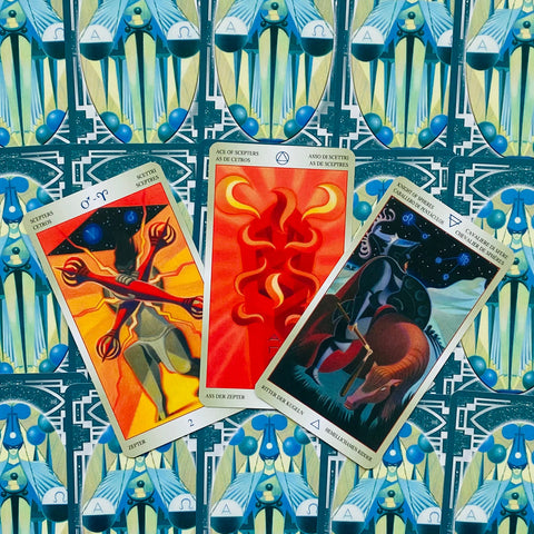 Tarot kortos trijų kortų išdėstymas: centre ryškiai raudonas Asas, kairėje ugninis Dvejetas, dešinėje Riteris ant mėlyno geometrinio nugarėlių fono