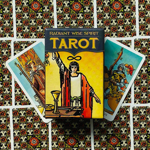 Taro kortos Radiant Wise Spirit dėžutė su geltonu viršeliu, dvi išlankstytos kortos priekyje ir raštuotas fonas