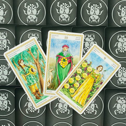 Tarot kortos – trijų Monetų rūšies kortų išdėstymas įstrižai su spalvingomis iliustracijomis ir juodomis nugarėlėmis