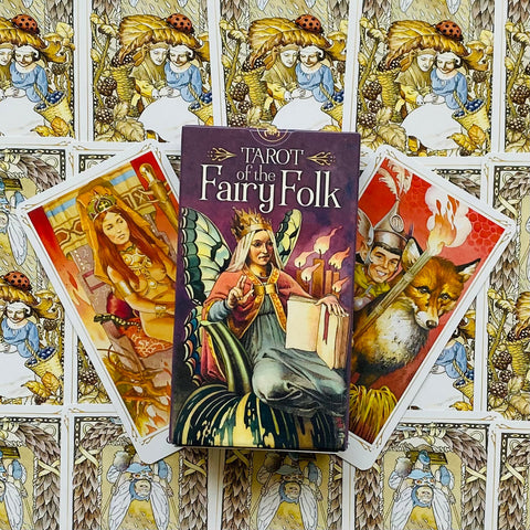 Taro kortos „Fairy Folk“ dėkle, matomas iliustruotas viršelis centre ir trys skirtingos atverstos kortos fone
