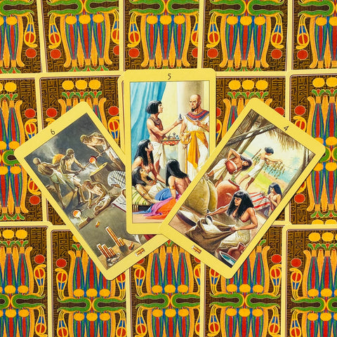 tarot kortos Egiptietiškos, trys atvertos kortos su geltonais kraštais padėtos ant spalvingo nugarėlių rašto