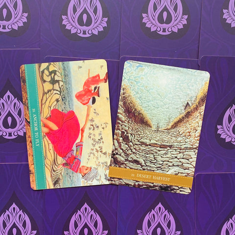 tarot kortos su dviem atvertais piešiniais: raudona „Anchor to Fly“ ir akmeninė „Desert Harvest“ ant violetinio fono