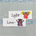 Dovanų etiketė su ranka pieštomis angelų iliustracijomis ir užrašais "Light" bei "Love", matomas priekinis dizainas