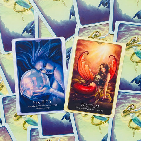 Tarot kortos, atverstos dvi: mėlyna Fertility korta ir raudona Freedom korta ant undinėlės nugarėlių