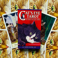Tarot kortos Cat's Eye, raudona dėžutė su juodai baltu katės piešiniu, centre ant paskleistų kortų fone, akcentuojant komplektą