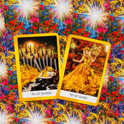 Tarot kortos geltonu rėmeliu — Ten of Swords ir Ten of Wands pora ant ryškaus gėlių fono, pabrėžianti skirtingus meninius dizainus ir spalvų kontrastą