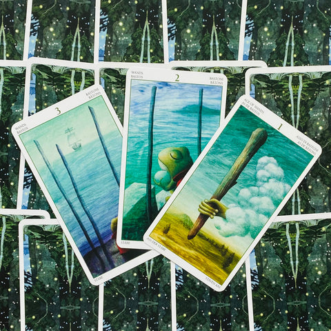 tarot kortos trijų lazdelės kortų išklotinė mėlyno‑žalių tonų, prisegtos iš viršaus ant tamsiai žalių raštuotų kortų fono