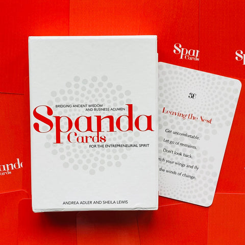 Spanda kortų rinkinys ant ryškaus raudono fono, baltos dėžutės priekis su raudonu logotipu ir matoma pavyzdinė kortelė dešinėje