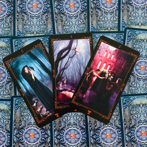 tarot kortos trijų kortų išklotinė su tamsiomis gotikinėmis iliustracijomis ant ornamentuoto kortų nugarėlių