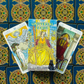 Universal Tarot geltonas dėklas su trimis didžiosios arkanos kortomis (Įsimylėję, Imperatorė, Hierofantas) ant raštuotų nugarėlių, rodoma dizaino ir spalvų variacija