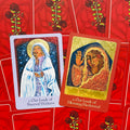 Taro kortos: dvi orakulų kortos (mėlyna Our Lady of Sacred Waters ir auksinė Blessing Bestowed) ant raudonos rožių nugarėlės