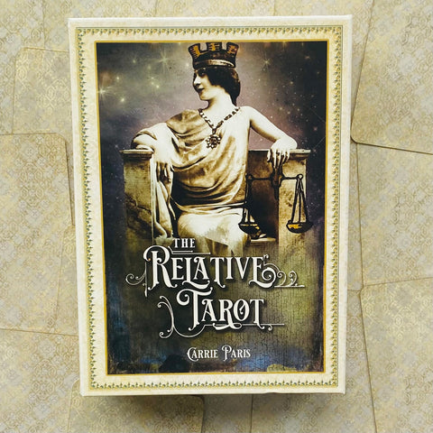 Kortų rinkinys The Relative Tarot Carrie Paris — kreminio dėklo priekinis viršelis su sėdinčios moters figūra ir svarstyklėmis, vintage stilius