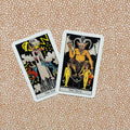 tarot kortos Rider‑Waite stiliaus, dvi didžiųjų arkų kortos The Tower ir The Devil ant raštuoto fono, nuo viršaus matomas kampinis vaizdas