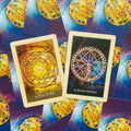 Orakulo kortos su dviem atverstais variantais – auksiniu Relic of Time dizainu ir tamsiai mėlynu Sacred Serpent mandala ant fono su kortų nugarėlėmis