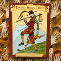 Produkto puslapyje — centrinis priekis raudonos‑rudos The English Magic Tarot dėžutės su iliustracija, fone kortų ir rankų raštas