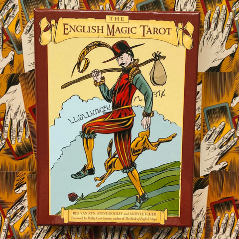 Produkto puslapyje — centrinis priekis raudonos‑rudos The English Magic Tarot dėžutės su iliustracija, fone kortų ir rankų raštas