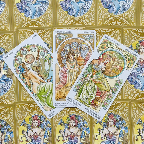 Tarot kortos Art Nouveau stiliaus, trys atverstos kortos (Karalius, Karalienė, Pentakliai) ant aukso raštuoto nugarėlių fono