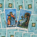tarot kortos Rider–Waite: dvi atverstos taurų kortos (Karalius ir Karalienė) ant melsvų nugarėlių, priekinis planas