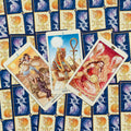 Tarot kortos su trimis atverstomis, spalvotomis iliustracijomis (Egipto moteris, karalienė, vyras) ant mėlyno‑auksinio nugarėlių
