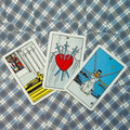 Tarot kortos Rider–Waite stiliaus, trijų kortų išklotinė su Trejais kardais centre, ryškūs raudoni ir mėlyni tonai ant languoto fono
