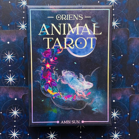 Tarot kortos Ambi Sun dėžutė su tamsiai mėlynu kosminiu dizainu, mėnuliu, žėrinčiu zuikiu ir gėlių vainiku priekinėje pusėje