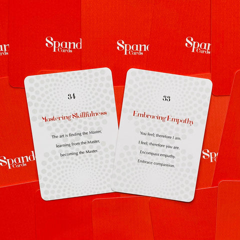 Kortos Spand Cards baltomis priekinių kortelių išklotėmis (nr.33 ir nr.34) ant raudono logotipuoto fono, matomi įkvepiantys užrašai