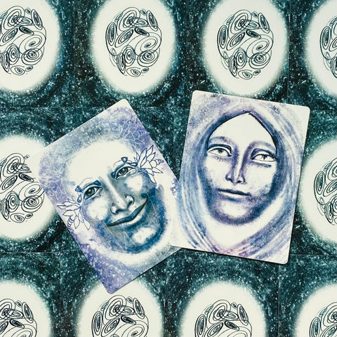 Tarot kortos su dviem violetinėmis ir mėlynomis veidų iliustracijomis, persidengiančios kampu ant žvaigždėto nugarėlių