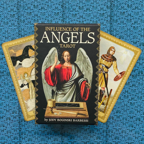 Tarot Influence of the Angels rinkinys su juodu dėklu ir dviem išskleistomis kortomis ant mėlyno rašto
