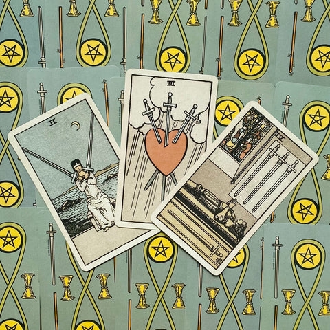 tarot kortos Rider–Waite, trijų kortų išdėstymas (Dviejų kardų, Trys kardai, Keturi kardai) ant žalių pentaklių nugarėlių iš viršaus