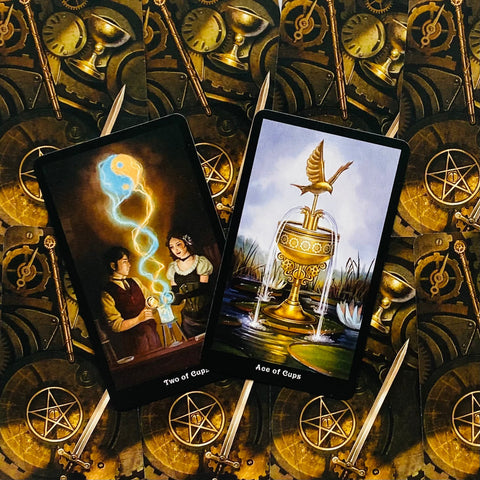 tarot kortos Steampunk rinkinys, centre parodytos Ace of Cups ir Two of Cups kortos su auksine mechanine nugarėle