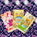 Tarot kortos trys spalvotos pasakų karalienės ir simboliai ant tamsaus žvaigždėto fono, kortos išdėstytos fane